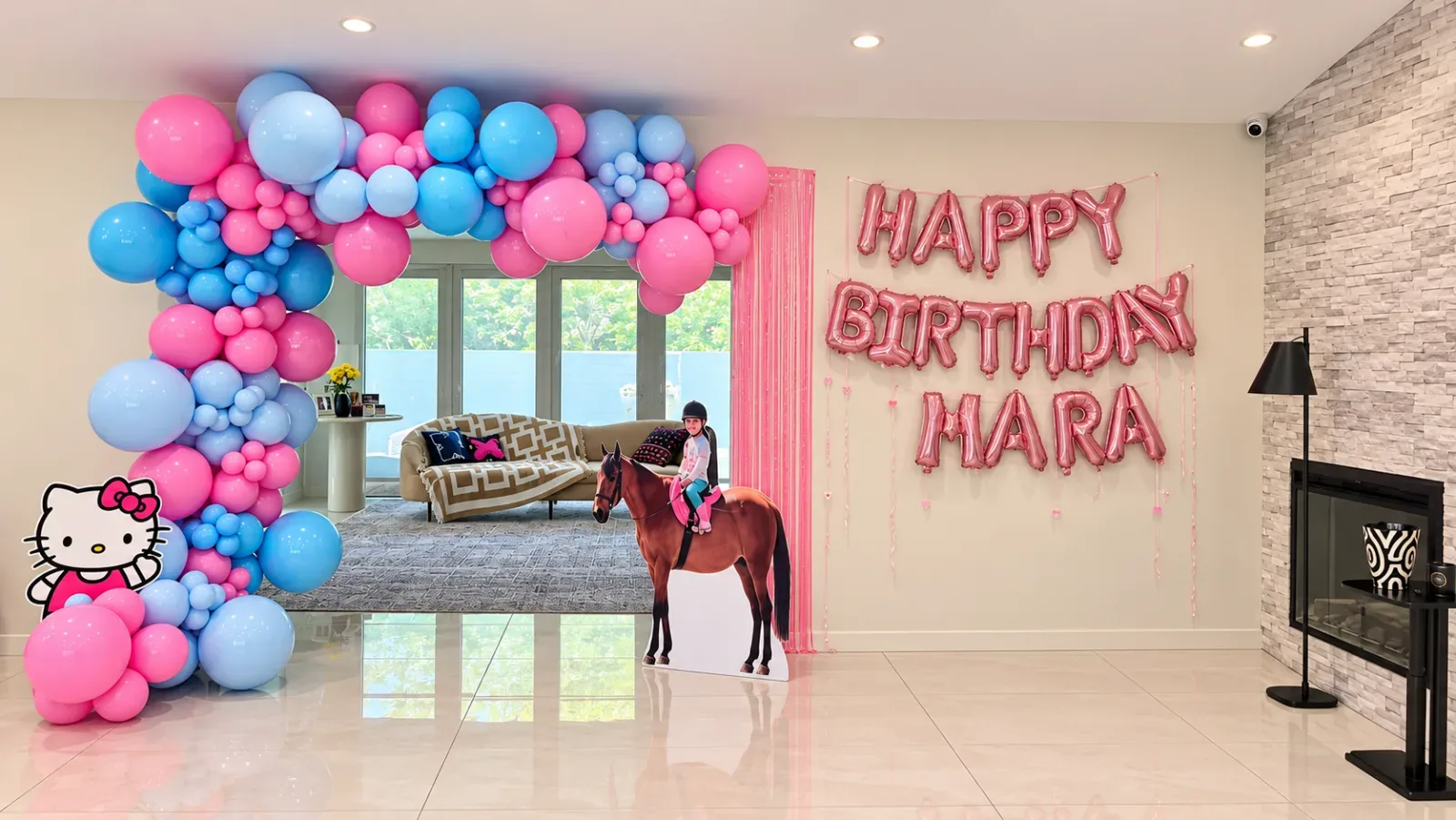 Decoración de cumpleaños Hello Kitty en Woodland Hills con arco orgánico de globos rosas y azules, letras personalizadas de Happy Birthday y figuras decorativas.